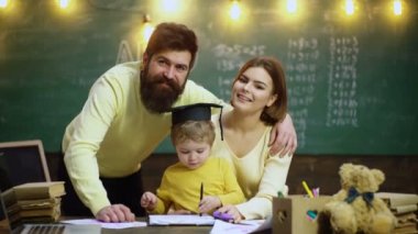 Genç bir aile ders çalışıyor. Mutlu aile çizim kitabı. Anne baba ve oğul kitap ev ödevini okuyorlar. Anne ve babalar, çocuk sahibi olmaktan gurur duyuyor.
