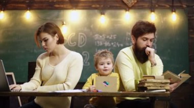 Çocuklar evde öğrenir ve öğrenirler. Aile eğitimi. Genç anne baba ve küçük anaokulu çocuğu masada birlikte otururlar.