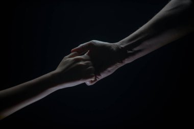Kurtuluşa uzanmak için kollarını uzat. Güçlü elini yaklaştır. İki el, bir arkadaşın koluna yardım, takım çalışması. Kurtarma, güç, el hareketlerine yardım etme. Siyah arkaplan