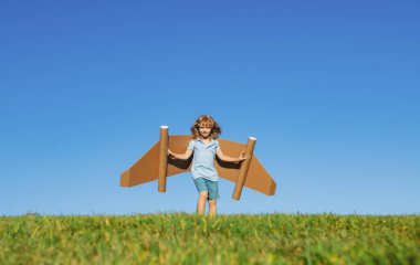 Gökyüzünde kanatları olan çocuk bir pilot hayal ediyor ve uçmayı hayal ediyor. Çocuk parkta karton oyuncak uçakla pilotçuluk oynuyor.