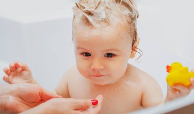 Child bathing. Baby showering. Portrait of kid bathing in a bath with foam clipart
