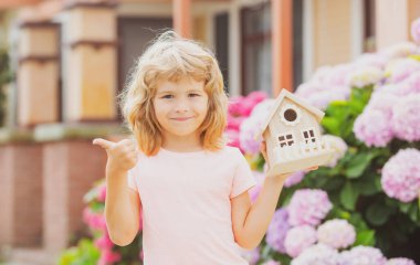 Ev bahçesinde küçük ev modeliyle oynayan sevimli bir çocuk. Çocuk bahçesinde ekoloji bölümü arka bahçeye karşı.