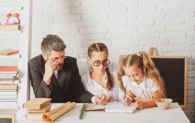 Sınıfta öğretmeni olan ilkokul öğrencileri. Babası liseli kızlara ders veriyor. Baba ve küçük çocuklar okulda. Kitap okumak ve yazmak