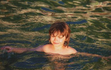 Mutlu çocuklar denizde oynar ve yüzer.