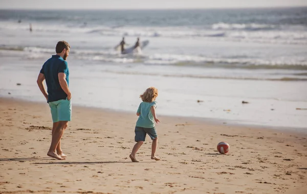 父と息子は夏休みにビーチでサッカーやサッカーをします 父と子供は屋外で楽しんでいます — ストック写真