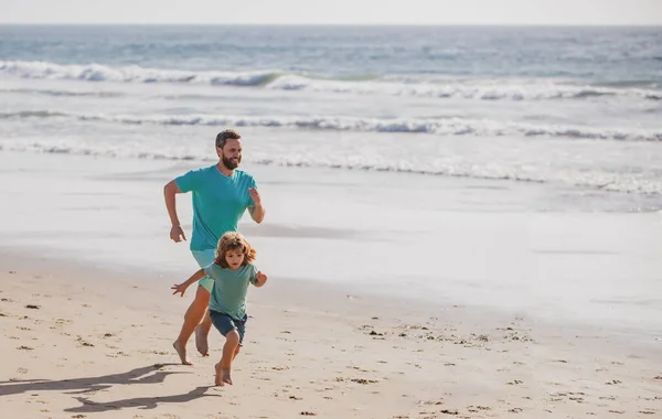 Father and son running on beach. Sport and healthy lifestyle, family jogging on the beach
