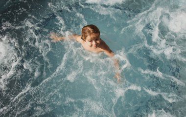 Çocuk tropik plajda yürüyor. Yaz tatilinde sahilde bir çocuk. Doğadaki çocuklar güzel deniz, kum ve mavi gökyüzü. Mutlu çocuklar deniz kenarında tatildeler, su kenarında yürüyorlar.