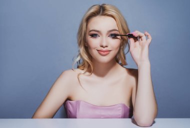 Uzun kirpikleri var. Rimel süren bir kız. Makyaj malzemeleri. Kadın güzelliği