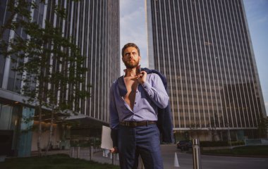 Modern bir açık uzay iş merkezinde yönetici. Dışarıda başarılı bir iş adamı, omuzlarında ceketle.