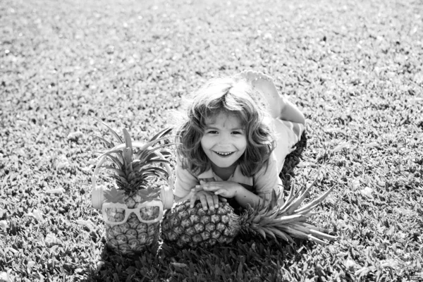 自然を背景にパイナップルを抱きしめる小さなブロンドの子供 小児性 健康的な栄養 子供たちの面白い顔を閉じて スペースをコピー — ストック写真
