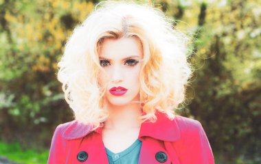 Bahar çiçekleri arka planında şehvetli genç bir kadın. Kıvırcık saçlı, bahar güzeli kız. Bahar makyajı.