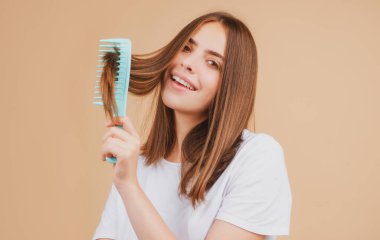 Saçlarını tarayan gülümseyen bir kadın. Güzel bir kız uzun saçlarını tarıyor.