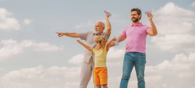 Üç farklı nesil. Büyükbaba ve çocuk. Açık havada oyuncak uçakla oynuyorlar.