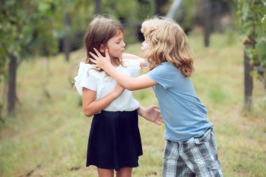 Çocuk ve kız bahar bahçesinde birbirlerine sevgiyle sarılıyorlar. Parkta sarılan iki küçük çocuk. Çocuklar dışarıda beraber oynuyorlar. Çocuklar öpüşüyor