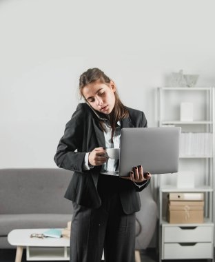 Ofis çalışanı kahve içiyor, telefonla konuşuyor, dizüstü bilgisayar kullanıyor. Ofisteki modern işyerinde çalışan çekici bir sekreter kadın. Ofisin içindeki güzel muhasebeci kız.