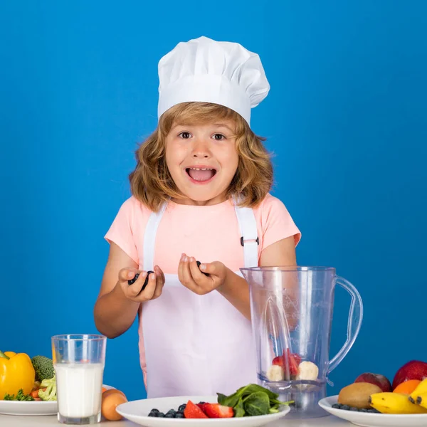 Excited funny chef cook. Portrait of chef child in cook hat. Cooking at home, kid boy preparing food from vegetable and fruits. Healthy eating