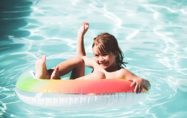 Yüzme havuzundaki çocuklar. Açık havada yaz. Mutlu çocuk yüzme havuzunda renkli yüzme yüzüğüyle oynuyor. Çocuk oyuncakları. Çocuklar tropikal tatil köylerinde oynarlar. Aile plaj tatili