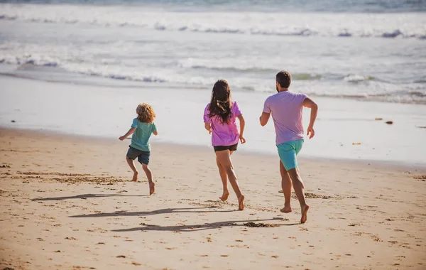 幸せな若い家族が走り 夏のビーチでジャンプします 親と一緒に子供が走ってジャンプします フレンドリーな家族と夏休みの概念 — ストック写真