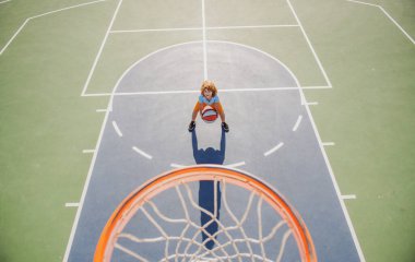 Çocuk bahçesinde basketbol oynayan çocuğun üzerinden açılı görüş