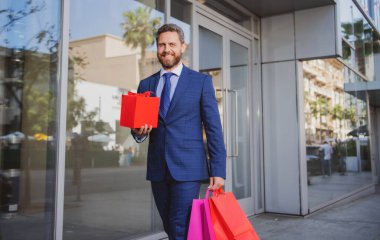 İş adamı yürüyor. Şehirde alışveriş yapan yakışıklı bir adam. Takım elbiseli bir iş adamının portresi.