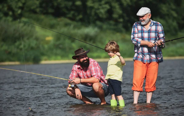 Man teaching kids how to fish in river. Father, son and grandfather fishing. Generations men. Three generations ages: grandfather, father and young teenager son