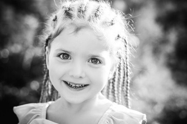 Child girl with stylish hair rope dreadlocks. Kid with fashionable hairstyle on blur background outdoor. Children beauty and fashion