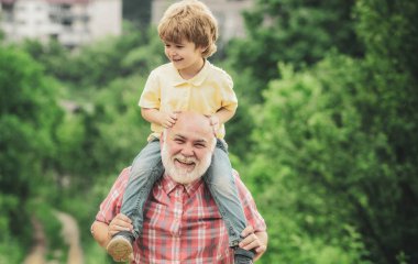 Mutlu aile - büyükbaba ve çocuk yazın çayırda doğada. Mutlu büyükbaba eğleniyor. Havaya fırlatıyor. Aile kavramı.