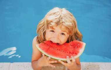 Komik şaşkın çocuk havuzun yanında karpuz yiyor.