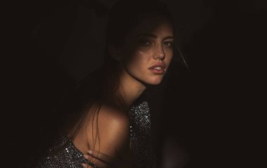 Kızların yüzü gölgeli, çekici bir kadın model. Gölgedeki kadın. Yüzünde gölgeler olan kadın model. Işıklı dramatik siyah stüdyoda baştan çıkarıcı ve şehvetli görünüyor.