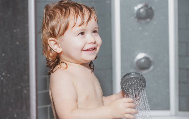 Çocuk sağlığı hizmetleri. Mutlu bebek köpüklerle oynayarak banyo yapıyor. Küvette küçük bir çocuk. Banyoda gülümseyen çocuk. Bebek yıkama ve banyo. Çocuklar bakım ve hijyen yapar.