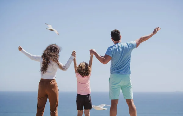 ビーチで家族のバックビュー 夏休みに人々 お父様 お母様 お子様が青い海に手をつなぐ 休暇旅行のコンセプト — ストック写真