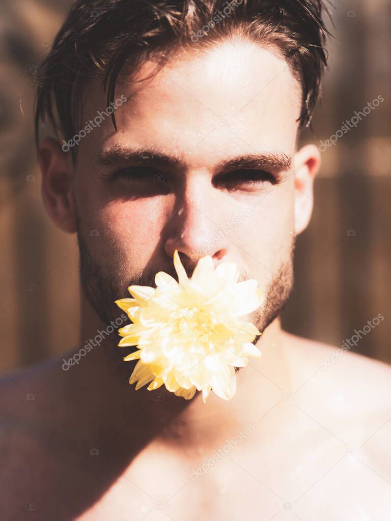 Man in love. Pride gay homosexual concept. Man face with flower in mouth, tongue. Handsome man close-up portrait