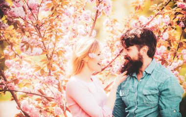 Çiçek ağacının yanında genç mutlu bir çift. Güneşli bahar gününde bir çift. Birbirine aşık romantik bir çift birbirine bakıyor. Mutlu Paskalyalar