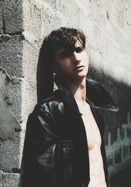 Gri duvara karşı şık bir genç adam. Kendine güvenen genç adam kameraya bakıyor.