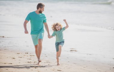 Baba ve oğul yaz plajında koşuyor. Mutlu aile kavramı