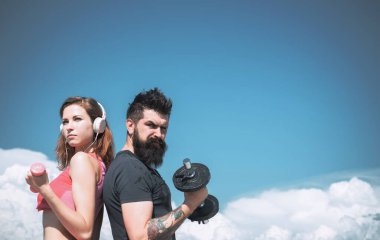 Dışarıda spor aletleriyle çalışan genç ve güçlü bir çift. Güzel mavi gökyüzü arka planında. Aktif yaşam tarzı ve spor aktiviteleri konsepti