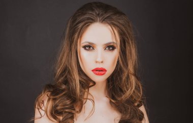 Yakından bir güzellik portresi. Kırmızı dudak makyajı. Parlak makyajlı genç bir kadın. Kırmızı ruj parlatıcısı.