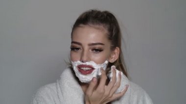 Yüzünde köpük ve jilet olan güzel bir kadın. Trans cinsiyet kavramı. Tıraş olan kadın