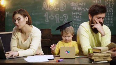 Çocuklar evde öğrenir ve öğrenirler. Sevimli küçük çocuk ailesinden öğreniyor. Anne, baba ve çocuklar evde resim çiziyorlar.