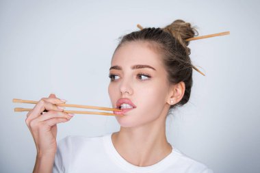 Suşi barındaki seksi genç kadın yemek çubuklarıyla dudaklarına dokunuyor. Suşi reklamı.
