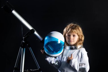 Çocuk uzayı keşfediyor. Uzay elbiseli ve teleskoplu şirin çocukların portresi. Kozmonotik gün konsepti. Astronomi ve astroloji kavramı