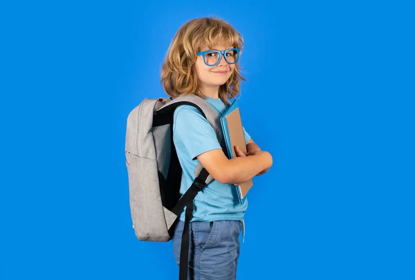 Back to school. Schoolboy with school bag hold book and copybook ready to learn. School children on isolated studio background. Portrait of happy smiling school kid. Positive emotions