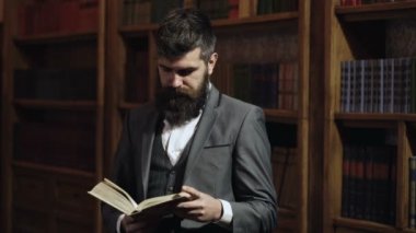 Kütüphanede olgun bir adam ve okumayı seviyor. Takım elbiseli sakallı adam memnun görünüyor. Keyif ve rahatlama, hobi konsepti. Edebiyat ve başarı. Hukuk ve adalet kavramı