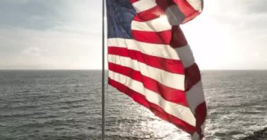 4 Temmuz. Ulusal Amerikan Bağımsızlık Günü kutlaması. Amerikan Bayrağı. Amerikan bayrağı dalgalanıyor, deniz ve günbatımı yakınlarında. ABD bayrağı dalgalanan bayrak direği