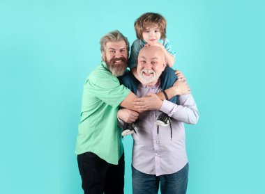 Büyükbaba, baba ve oğul kucaklaşıp kucaklaşıyorlar. Babalar Günü konsepti. Farklı yaşlardaki erkekler birbirlerine sarılıyorlar. Büyük ebeveynli ebeveynlik. Aile şefkati, çocuk sevgisi, sevgi