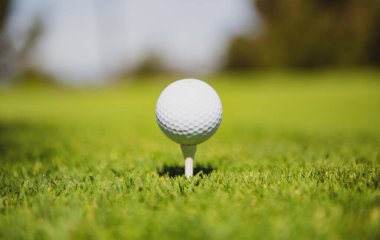 Golf topuyla birlikte yeşil çimenler güneş ışığında yumuşak odak noktasında. Golf kulübü konsepti için golf sahası