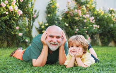 Mutlu aile torunu tatilde dedesine sarılır. Büyükbabam ve torunum birlikte vakit geçiriyorlar. Mutlu aile babası ve çocuğu yeşil çimlerin üzerinde uçurtmayla çayırda