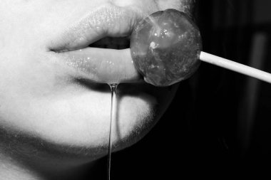 Şeker yalıyorum. Lolipop modeli. Kadın dudakları şeker emiyor. Oral seks konsepti. Kırmızı dudaklı çekici manken eşofman altı yiyor lolipop