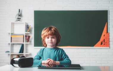 Bireysel ders. Sınıfta, tahtaya yakın arkadaş canlısı bir çocuk. Küçük çocuk dijital tabletle oynuyor. Okulda tabletli okul çocuğu.