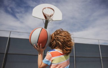 Küçük çocuk basket topuyla basketbol oynuyor. Basketbol çocuk okulu